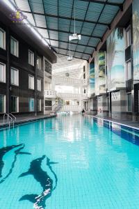 a large swimming pool with a person in the water at Crown Victoria Hotel Tulungagung in Tulungagung