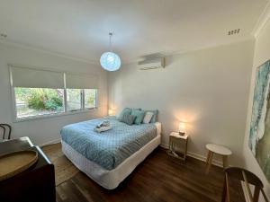 1 dormitorio con 1 cama con edredón azul y ventana en Barefoot Beach Cottage, en Geographe