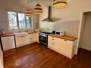 a kitchen with white cabinets and a stove top oven at Barefoot Beach Cottage in Geographe