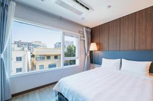 a bedroom with a bed and a large window at Jin Motel in Seogwipo