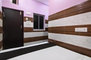 a locker room with a black door and brown and white tiles at Super OYO PPS NEST Guest House in Kolkata