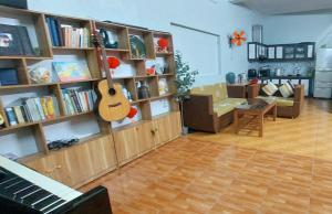 a living room with a guitar on a book shelf at LeMin Homestay in Hai Phong