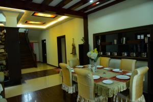 a dining room with a table and chairs and a staircase at Serenity Cottage Luxury Homestay Virajpet in Virajpet