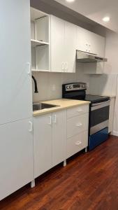 a kitchen with white cabinets and a sink and a stove at Newly renovated Elephant Suite two rooms close to banff and business center in Calgary