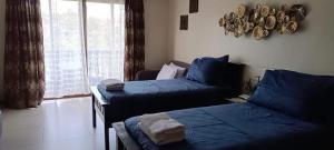 a bedroom with two beds with blue sheets and a window at Carol Crosswinds Tagaytay in Cavite