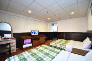 ein Hotelzimmer mit 2 Betten und einem TV in der Unterkunft 知本溫泉-彩溱旅宿 in Wenquan