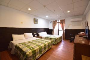 ein Hotelzimmer mit 2 Betten und einem Schreibtisch in der Unterkunft 知本溫泉-彩溱旅宿 in Wenquan