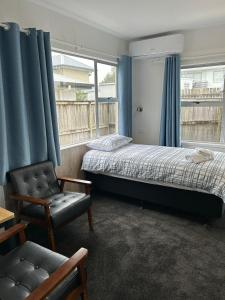 a bedroom with two beds and a chair and a window at Avon Apartments in Hamilton