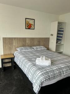 a bedroom with a bed with two towels on it at Avon Apartments in Hamilton