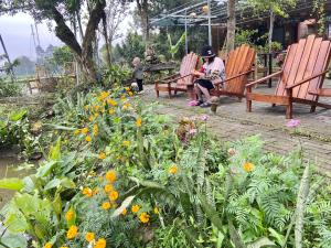 a woman sitting on a bench in a garden with flowers at Tam Coc Mountain View Homestay in Ninh Binh