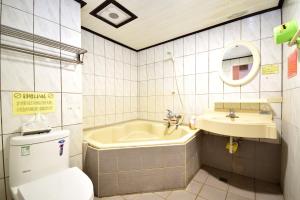 ein Badezimmer mit einer Badewanne, einem WC und einem Waschbecken in der Unterkunft 知本溫泉-彩溱旅宿 in Wenquan