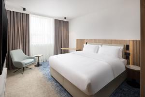 a bedroom with a large white bed and a chair at Courtyard by Marriott Cluj - Napoca Downtown in Cluj-Napoca