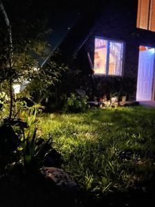 a yard with grass and a house with a lit up window at Cabaña María in Siguatepeque