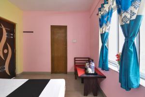 a bedroom with a bed and blue curtains and a table at SPOT ON Shree Balaji Hotel in kolkata