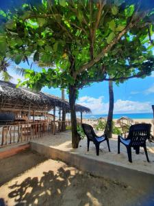 two black benches sitting on a sidewalk near the beach at La-Vira Beach Villa in Hikkaduwa