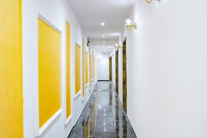 a hallway with yellow and white walls and a tile floor at Hotel Gorrion in Mumbai