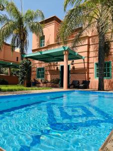 a swimming pool in front of a house with palm trees at Charming Villa with Pool, Garden and Pingpong in Marrakesh
