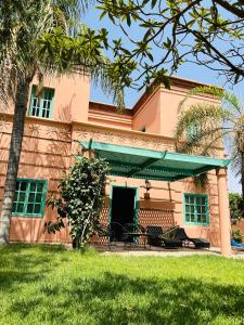 Charming Villa with Pool, Garden and Pingpong في مراكش: منزل أمامه نخلة