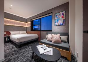une chambre d'hôtel avec un lit, une table et un canapé dans l'établissement HOTEL GRAPHY Shibuya, à Tokyo