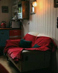 een bed bedekt met een rode deken in een keuken bij Quaint, rustic cabin with period features & stunning views in Llangadog