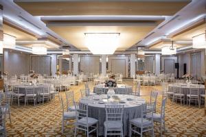 un salón de banquetes con mesas y sillas blancas en Anemon Grand Adana Otel, en Adana