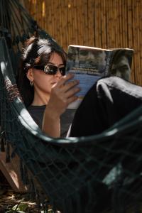 a woman sitting in a hammock reading a book at Destino26 Hostel in Montevideo