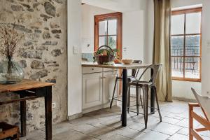 una cucina con tavolo, sedie e parete in pietra di Domaine de Roquenégade - Piscine, sauna et bain nordique a Pradelles-en-Val Altre 8 foto
