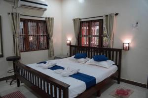een slaapkamer met een groot bed met blauwe en witte kussens bij Redstone House by Oxystays Home Stay in Ganpatipule