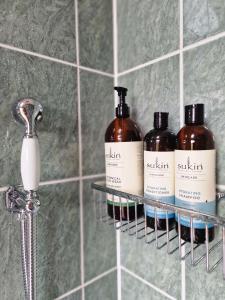 three bottles of soap on a shelf in a bathroom at Quaint, rustic cabin with period features, stunning views & hot tub in Llangadog