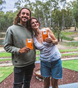 a man and a woman holding up orange boxes at Tocumwal Chocolate School Glamping in Tocumwal