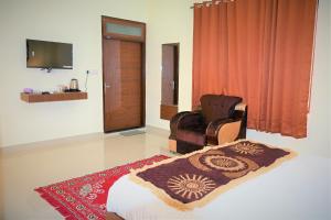 ein Schlafzimmer mit einem Bett, einem Stuhl und einem TV in der Unterkunft Ranthambhore Nature Farm in Sawāi Mādhopur