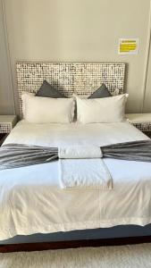 a white bed with two towels on top of it at PLANES in Kokstad