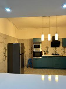 una cucina con armadi verdi e frigorifero di Le bonheur a Dzaoudzi