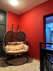 una sedia di vimini in una stanza con una parete rossa di Le bonheur a Dzaoudzi