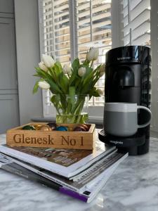 a table with a coffee mug and a vase of flowers at Glenesk No 1 , Woodhall Spa in Lincolnshire