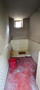 Baño sucio con suelo rojo y ventana en Bhumika Home Stay, en Kapkot