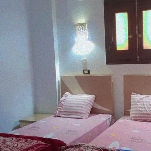a room with two beds and a light on the wall at Nubian Queen Guest House in Aswan