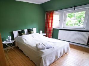 a green bedroom with a white bed and a window at Sophienhof Lieselotte in Neuenkirchen