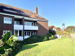 a brick house with a green lawn in front of it at Holiday apartment sea air in Langeoog