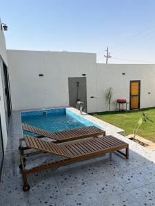a swimming pool with a bench in front of a house at شاليهات بالما in Al Hofuf