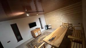 Zimmer mit einem Holztisch und Stühlen sowie einem TV. in der Unterkunft Parusa Burgulyuk in Birgulyuk