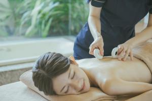 北中城村的住宿－EM Wellness Kurashinohakko Lifestyle Resort，一位女性从治疗师那里得到按摩
