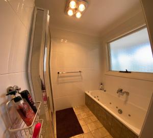 baño con ducha y bañera y ventana en Holiday house, en Blackheath