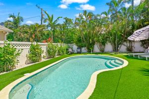 a swimming pool in a yard with grass and trees at The Cottage on Pine - Luxury Boho Beach Cottage wPvt Heated Pool On Pine Ave in Anna Maria