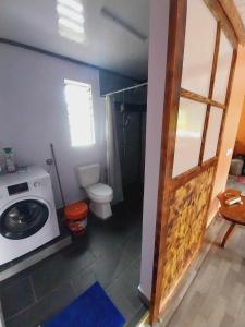 a bathroom with a washing machine and a toilet at Marupo Room in Fare