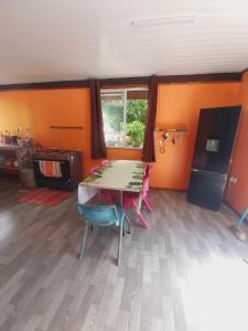 um quarto com uma mesa e cadeiras num quarto com paredes cor-de-laranja em Marupo Room em Fare