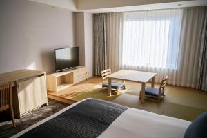 ein Hotelzimmer mit einem Tisch und einem TV in der Unterkunft Narita Tobu Hotel Airport in Narita