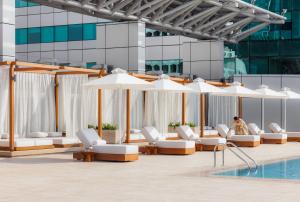 uma piscina com espreguiçadeiras brancas e guarda-sóis em Jumeirah Living World Trade Centre Residence, Suites and Hotel Apartments em Dubai