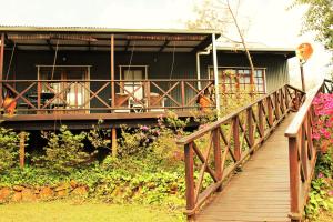 une passerelle en bois menant à une maison avec balcon dans l'établissement Mill Cottages, à Lidgetton