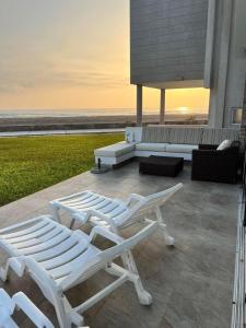 2 chaises longues blanches et un canapé sur la terrasse dans l'établissement Casas y Dptos de Hotel, Acceso a VPX Hotel, AC, Parrilla y piscina privada, à Asia